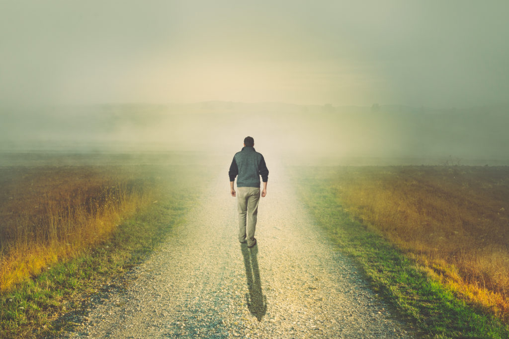 Man walking to the light on a dirt road - Blue Ridge Christian News