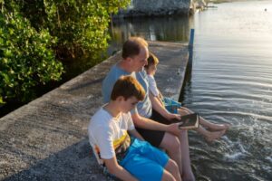 dad reading Bible to kids by lake